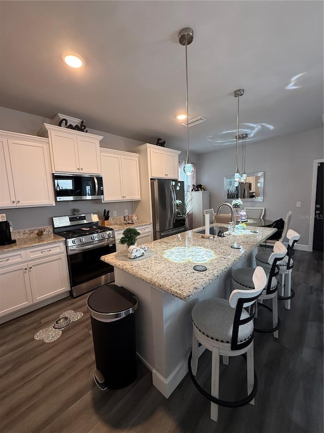 kitchen with appliances with stainless steel finishes, a breakfast bar area, white cabinetry, and a sink
