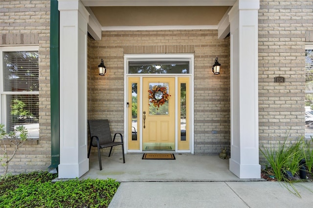 entrance to property featuring a porch and brick siding