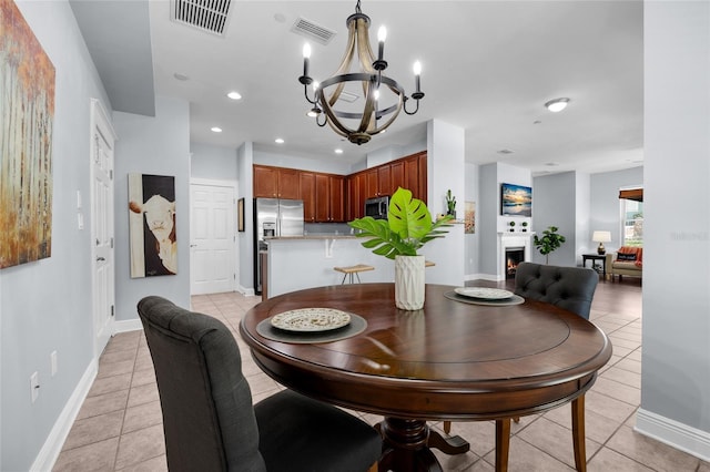 dining area with light tile patterned floors, a chandelier, recessed lighting, a warm lit fireplace, and baseboards