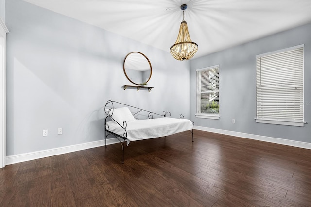bedroom featuring wood finished floors, baseboards, and a chandelier