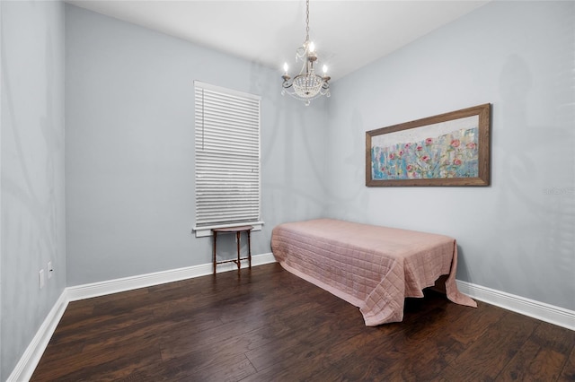 bedroom with a chandelier, wood finished floors, and baseboards