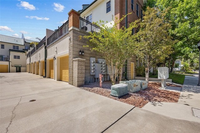 view of home's exterior with a garage, driveway, stucco siding, and a balcony