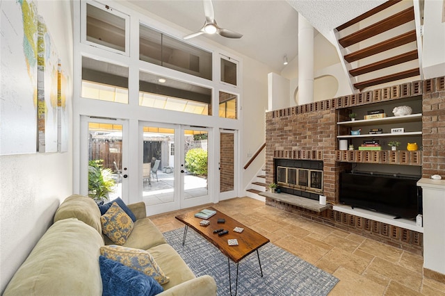 706 NE 1st St Unit 706, Gainesville, FL 32601 - living room featuring stone tile floors, a brick fireplace, french doors, a ceiling fan, and high vaulted ceiling