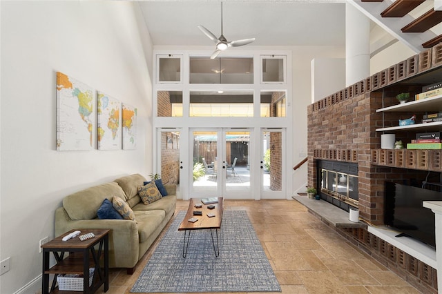 706 NE 1st St Unit 706, Gainesville, FL 32601 - living area with stone tile floors, ceiling fan, a fireplace, french doors, and a high ceiling