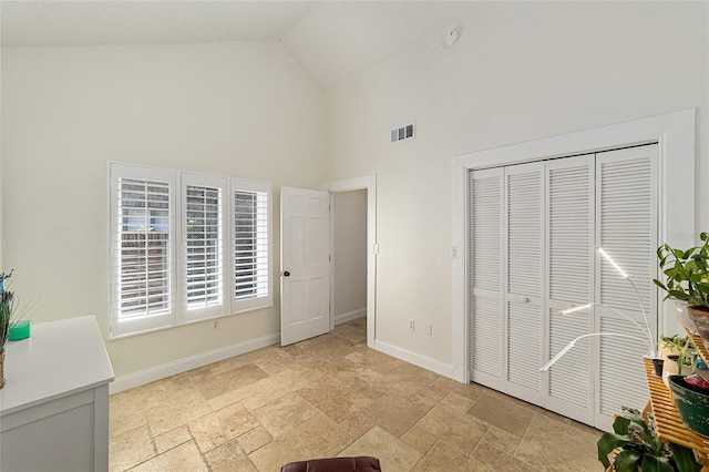706 NE 1st St Unit 706, Gainesville, FL 32601 - bedroom with stone tile floors, visible vents, high vaulted ceiling, and baseboards