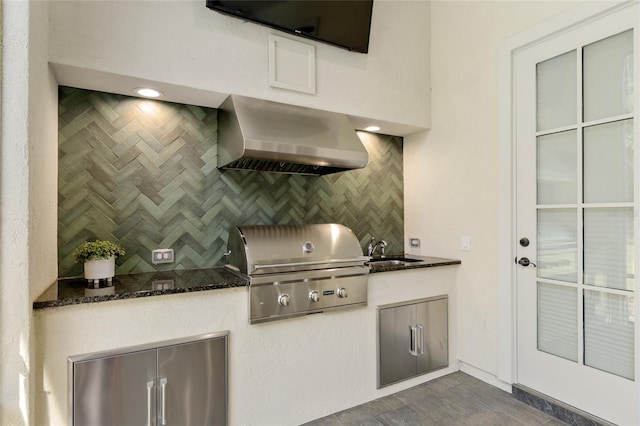 14819 NW 21st Ave, Newberry, FL 32669 - kitchen featuring dark stone countertops, backsplash, stainless steel refrigerator, a sink, and wall chimney exhaust hood