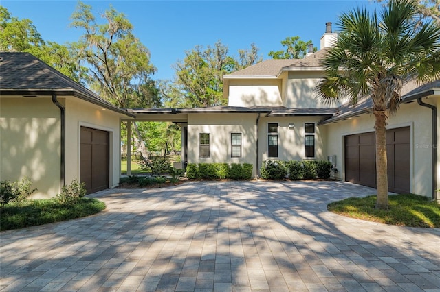 14819 NW 21st Ave, Newberry, FL 32669 - view of front of home with roof with shingles, a chimney, a garage, stucco siding, and decorative driveway