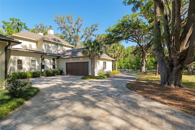 14819 NW 21st Ave, Newberry, FL 32669 - view of front facade featuring a chimney, fence, stucco siding, decorative driveway, and a garage