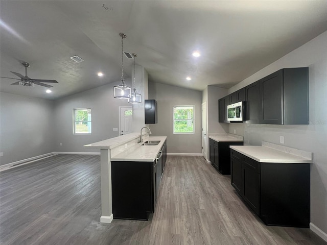 kitchen featuring stainless steel microwave, baseboards, a sink, and light wood-type flooring
