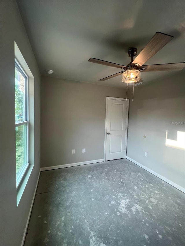 empty room featuring baseboards, ceiling fan, and a healthy amount of sunlight