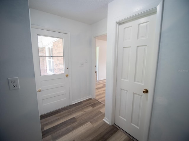 doorway with dark wood-type flooring and baseboards