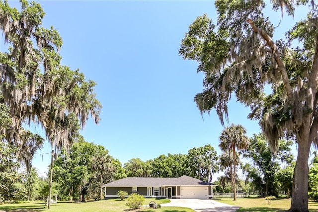 ranch-style house featuring a garage, driveway, a front yard, and fence