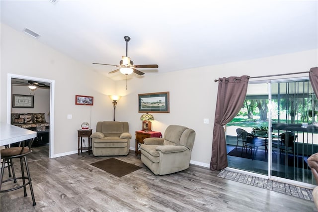 living area featuring vaulted ceiling, a ceiling fan, wood finished floors, baseboards, and visible vents