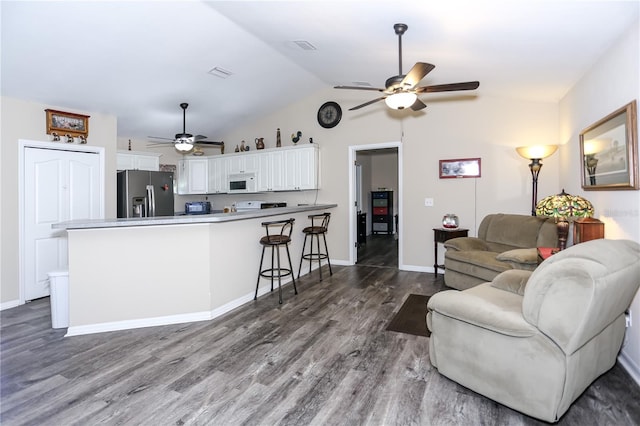 living room with ceiling fan, vaulted ceiling, wood finished floors, and visible vents