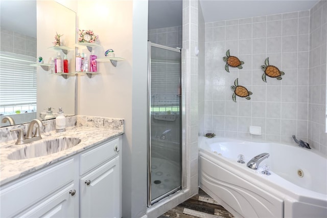 full bathroom with a tub with jets, vanity, and a stall shower