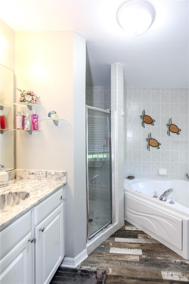 bathroom with a shower stall, a garden tub, vanity, and wood finished floors