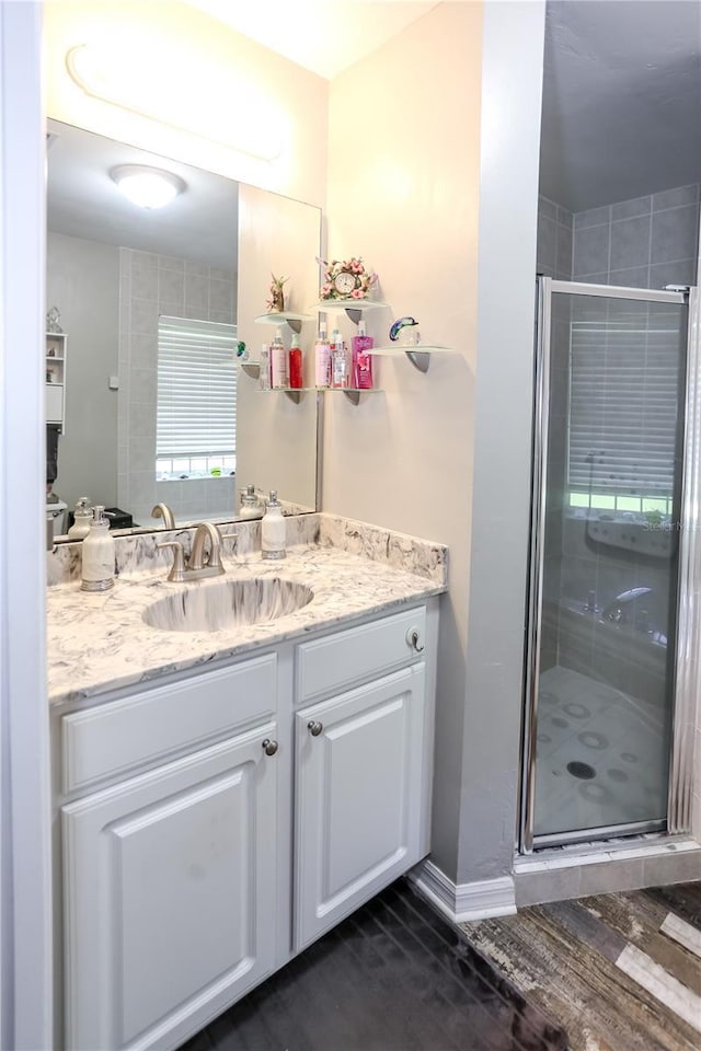 bathroom with a shower stall, baseboards, vanity, and wood finished floors