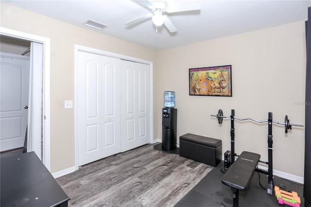 exercise area with wood finished floors, visible vents, baseboards, and ceiling fan