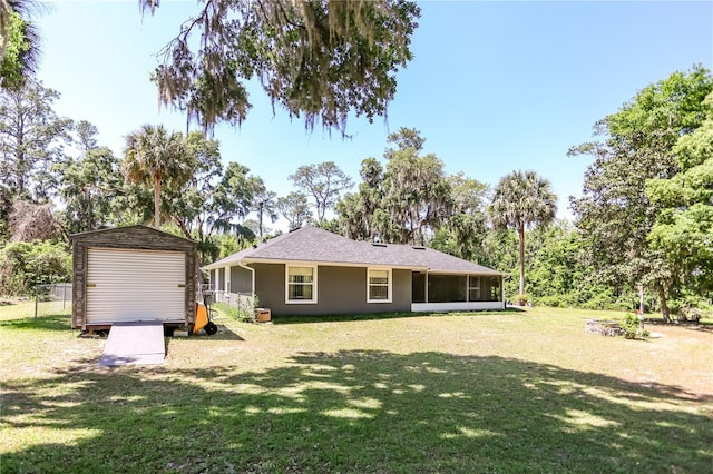 back of house with stucco siding, a sunroom, a yard, and a storage unit