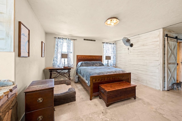 bedroom with wooden walls and a barn door