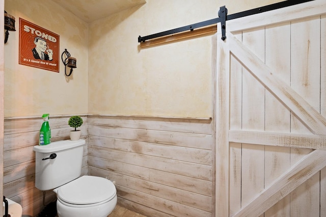 bathroom featuring toilet and a wainscoted wall