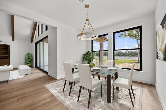 dining room with an inviting chandelier, baseboards, a water view, and light wood finished floors