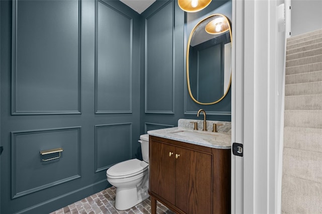 bathroom with vanity, brick floor, and toilet