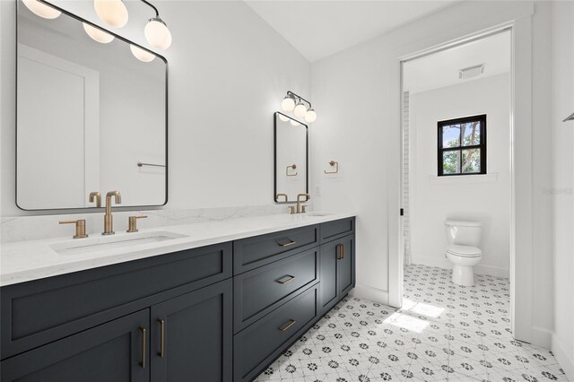 full bath featuring double vanity, toilet, baseboards, and a sink