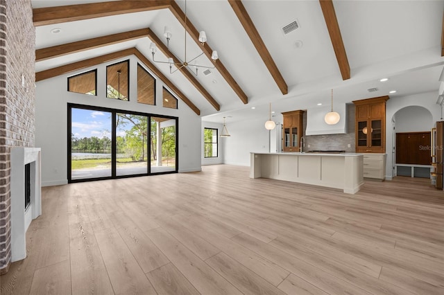 unfurnished living room with visible vents, a fireplace, high vaulted ceiling, and beamed ceiling
