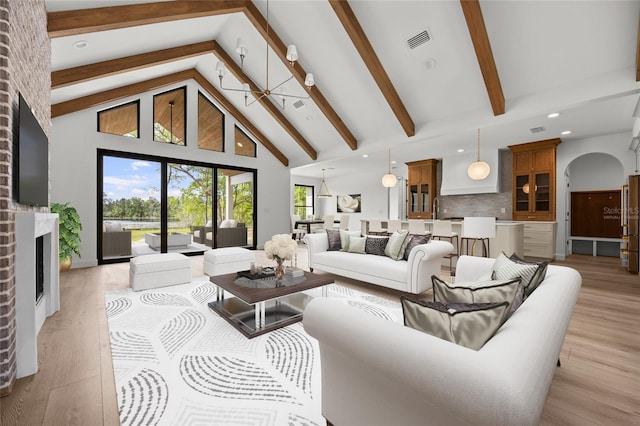 living room with visible vents, light wood-style flooring, beam ceiling, and high vaulted ceiling
