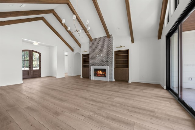 unfurnished living room with beam ceiling, french doors, baseboards, light wood-type flooring, and a tile fireplace