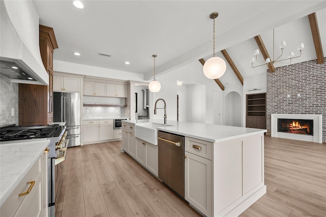 kitchen with visible vents, high end appliances, a sink, premium range hood, and light wood-style floors