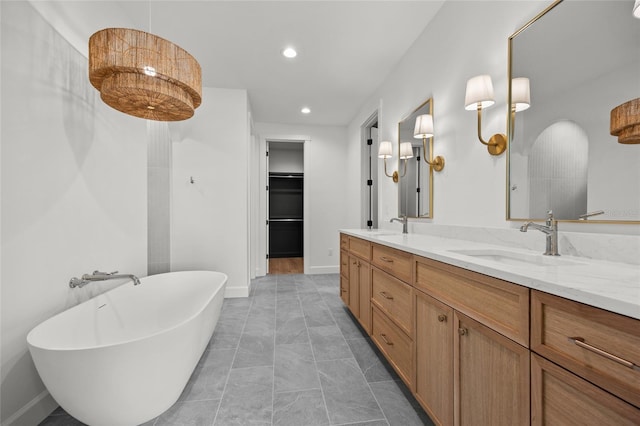 full bathroom featuring a walk in closet, a sink, double vanity, recessed lighting, and a freestanding tub