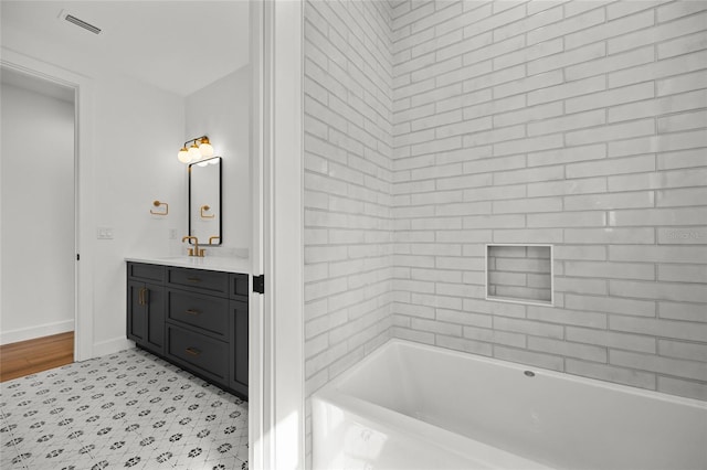 full bath with vanity, baseboards, a bathtub, and visible vents