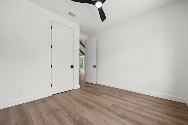 unfurnished bedroom featuring baseboards, wood finished floors, and visible vents