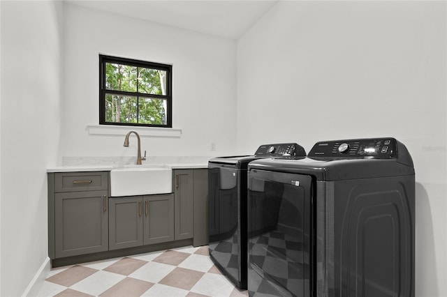washroom with cabinet space, a sink, baseboards, light floors, and separate washer and dryer