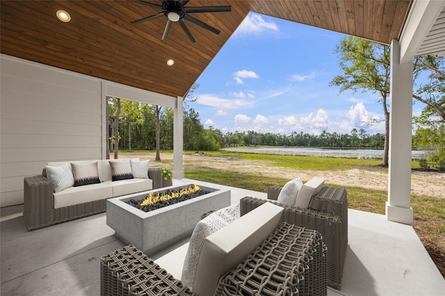view of patio / terrace featuring a ceiling fan, an outdoor living space with a fire pit, and a water view