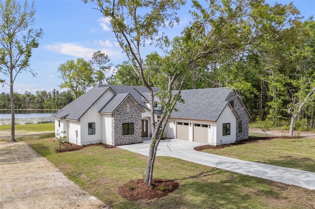 modern inspired farmhouse with board and batten siding, driveway, a water view, a shingled roof, and stone siding