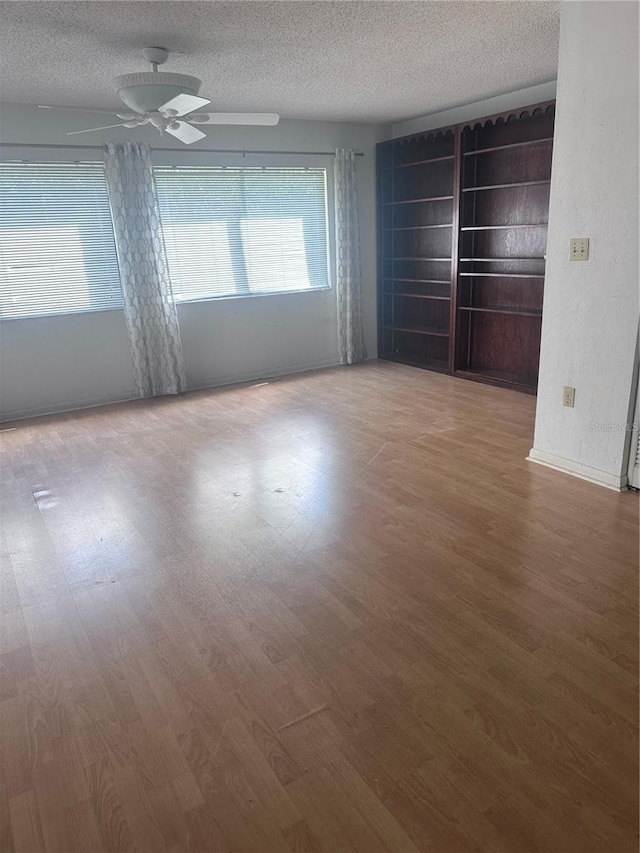 4606 NW 41st Pl Unit 107, Gainesville, FL 32606 - spare room featuring baseboards, ceiling fan, a textured ceiling, and wood finished floors