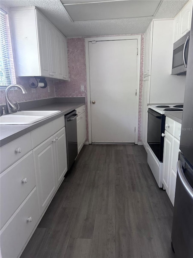 4606 NW 41st Pl Unit 107, Gainesville, FL 32606 - kitchen featuring white cabinets, dark wood-style flooring, appliances with stainless steel finishes, a sink, and light countertops