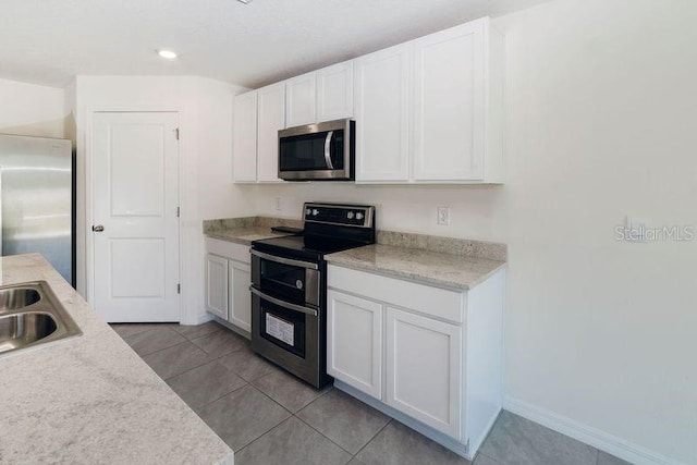 6683 SE 3rd Loop, Ocala, FL 34472 - kitchen featuring stainless steel appliances, light tile patterned flooring, light countertops, white cabinets, and baseboards