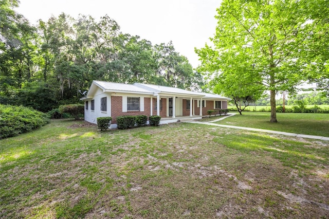 3436 SW 20th St, Gainesville, FL 32608 - ranch-style home with brick siding, metal roof, a porch, and a front lawn