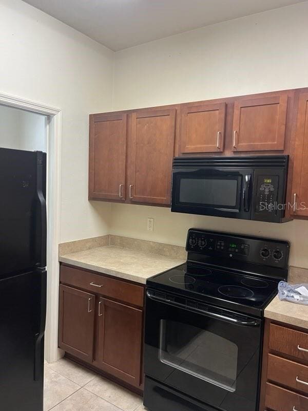 2927 SW 35th Pl Unit 115, Gainesville, FL 32608 - kitchen featuring light tile patterned floors, light countertops, and black appliances