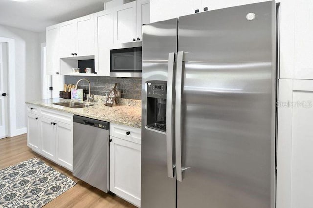 418 40th Ave S, Saint Petersburg, FL 33705 - kitchen featuring stainless steel appliances, a sink, backsplash, light wood finished floors, and white cabinetry