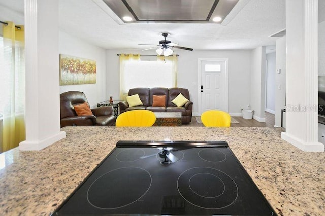 418 40th Ave S, Saint Petersburg, FL 33705 - kitchen with black electric stovetop, wood finished floors, baseboards, decorative columns, and light stone countertops