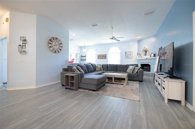 6114 NW 35th St, Gainesville, FL 32653 - living area with visible vents, baseboards, light wood finished floors, a fireplace, and a ceiling fan