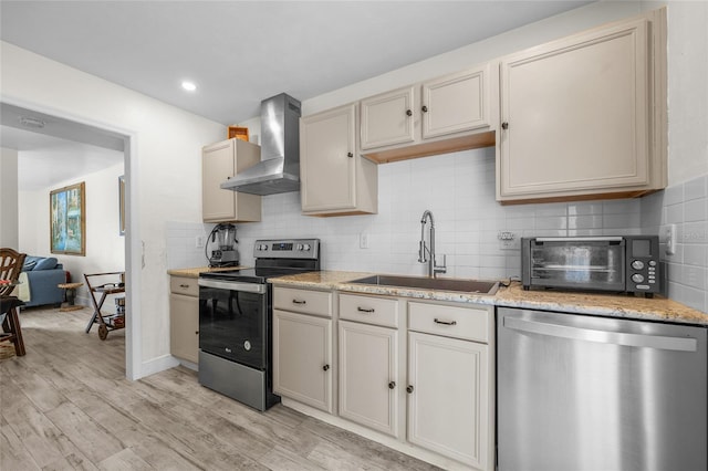 507 NW 39th Rd Unit 317, Gainesville, FL 32607 - kitchen featuring stainless steel appliances, a sink, wall chimney range hood, light wood-style flooring, and backsplash
