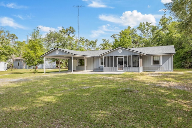 back of property featuring a sunroom, a yard, a shingled roof, and an attached carport