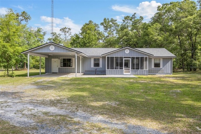 back of house with a lawn, driveway, a carport, and roof with shingles