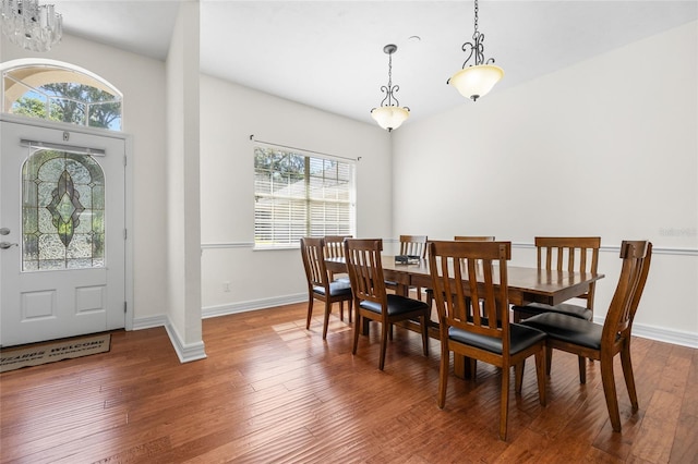 dining space with healthy amount of natural light, wood finished floors, a chandelier, and baseboards